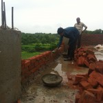Laying bricks for the parapet around the roof of the boys dorm.